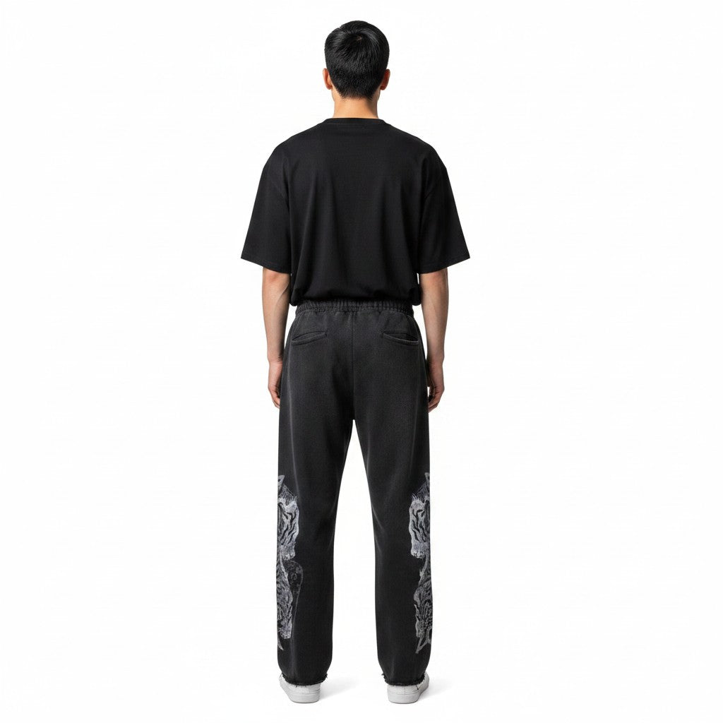 Hombre de espaldas vistiendo pantalones de chándal negros The Hype Company con estampado de tigres en las piernas