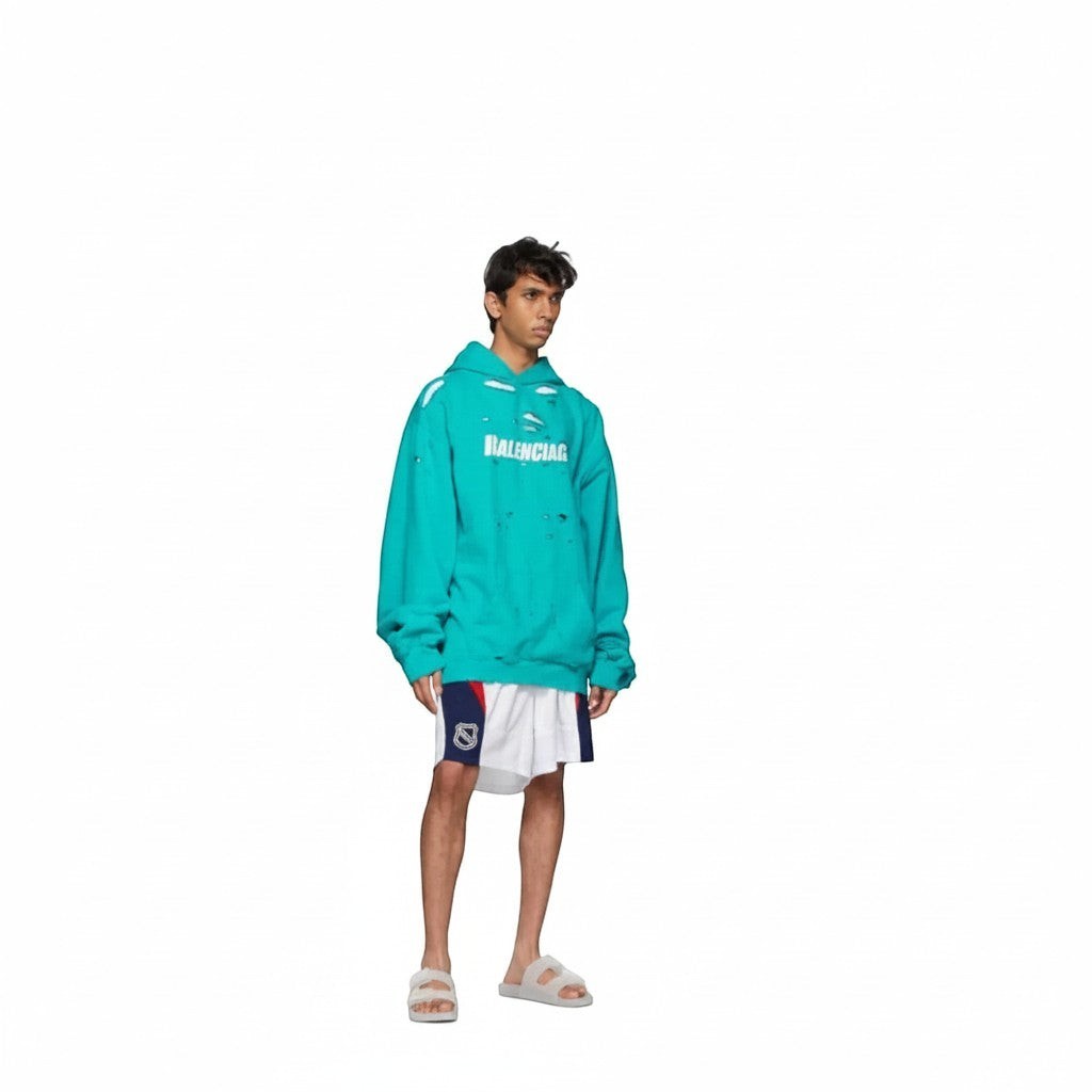 The Hype Company: Hombre con sudadera verde azulado desgarrada de Balenciaga y pantalones cortos de hockey blancos con detalles azules y rojos.