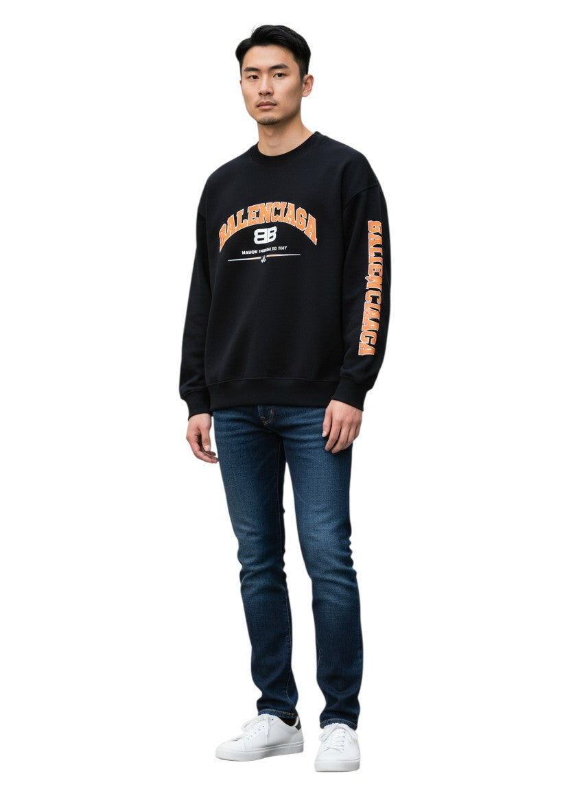 Hombre vistiendo sudadera negra The Hype Company Balenciaga Maison Le Fondee con logo naranja y jeans azules