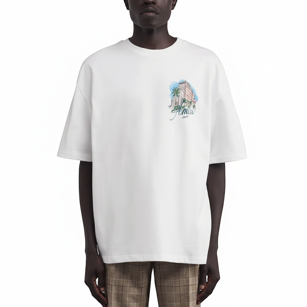 Camiseta blanca de The Hype Company con estampado de hotel y palmeras, cuello redondo y manga corta.