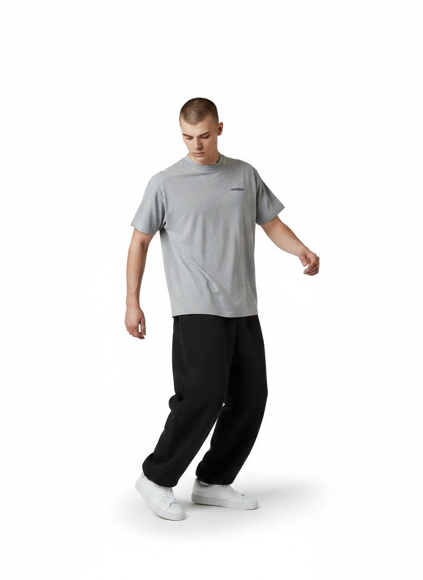 Hombre vistiendo camiseta gris de The Hype Company con logo pequeño en el pecho y pantalones negros holgados