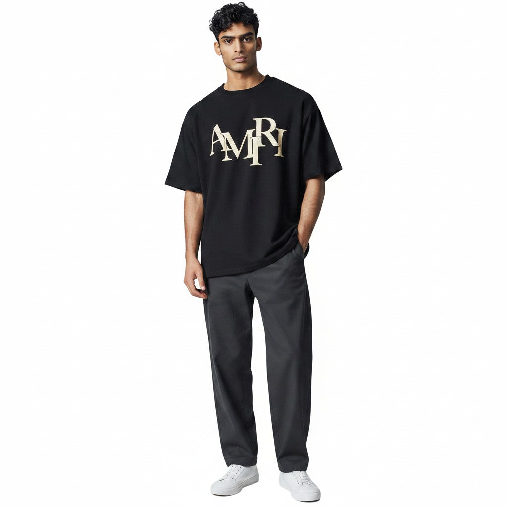 The Hype Company camiseta negra de manga corta con logo AMIRI escalonado en color dorado.