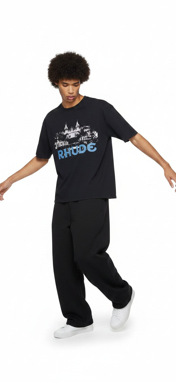 Modelo vistiendo camiseta negra The Hype Company Rhude Casino con estampado gráfico en el pecho y pantalones negros