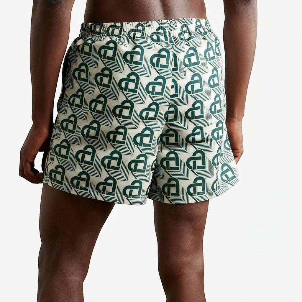 The Hype Company green monogram swim shorts with an all-over heart pattern on a cream background.