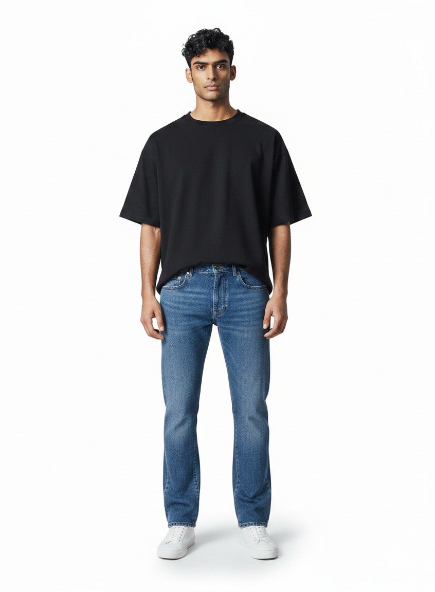 Modelo masculino vistiendo jeans azules ajustados y camiseta negra de The Hype Company sobre fondo blanco