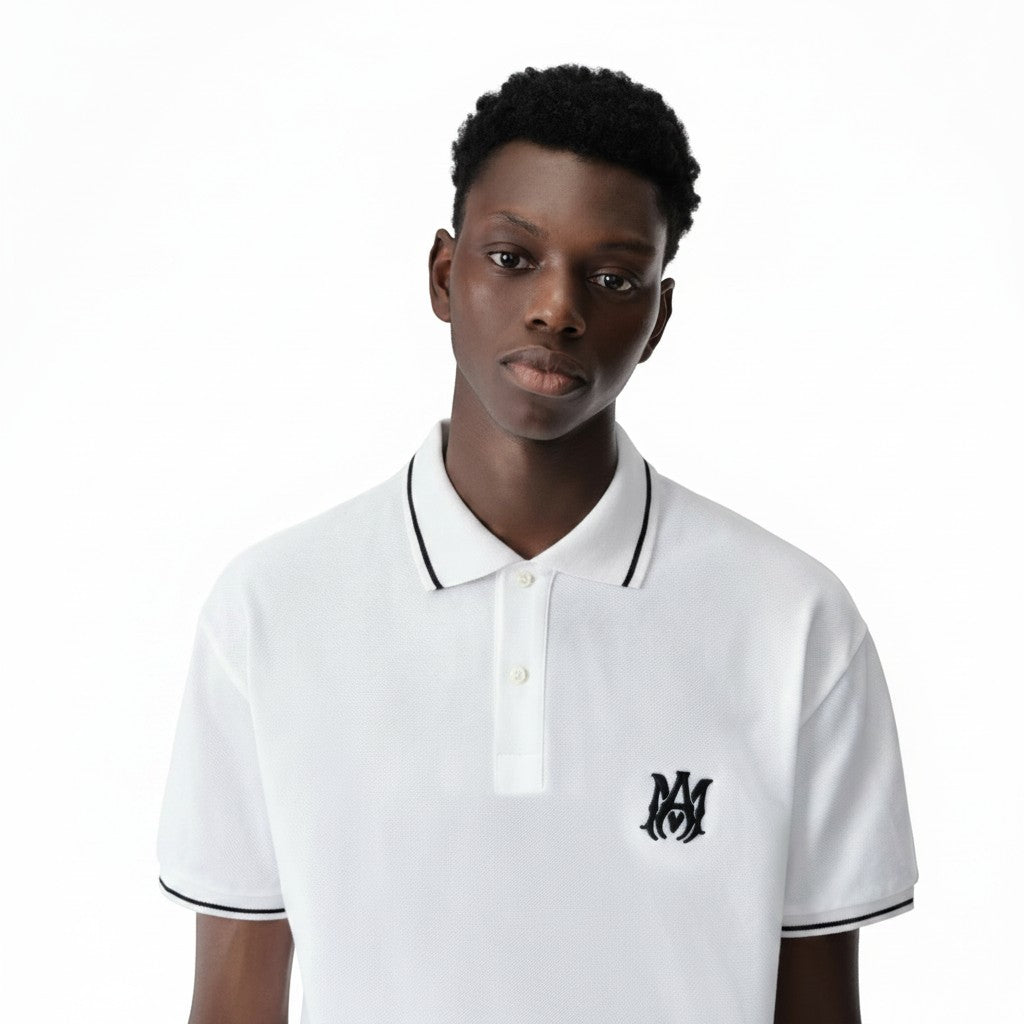 The Hype Company polo blanco de algodón con logo AMIRI bordado en negro y ribetes negros en cuello y mangas.