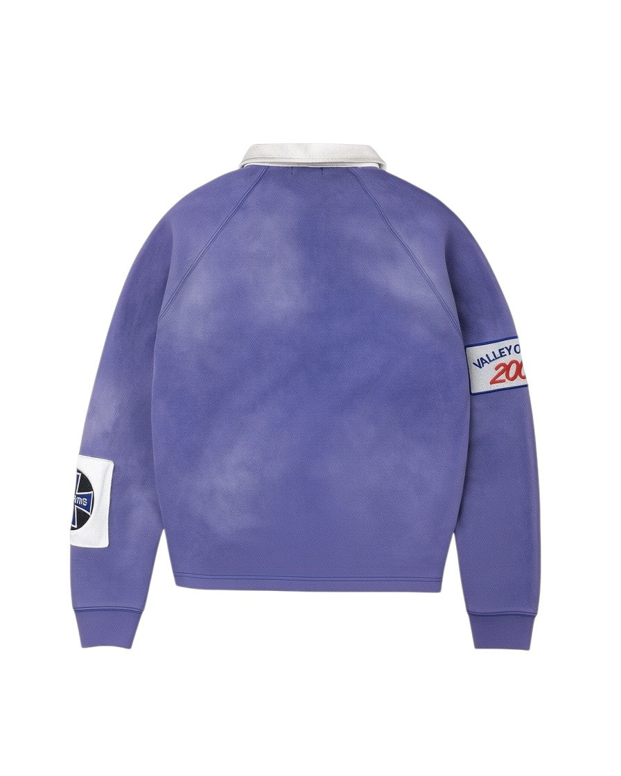 Vista trasera del polo de rugby de manga larga The Hype Company en azul con cuello blanco y parches gráficos