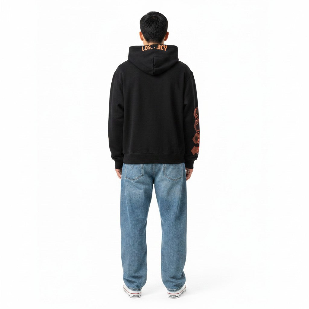 Hombre de espaldas vistiendo sudadera negra con cremallera The Hype Company con estampado naranja en capucha y manga